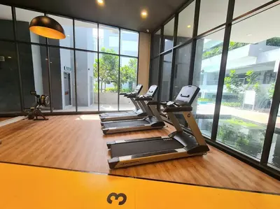 a row of treadmills in a gym with windows at Muji Tiny Studio Near KLCC in Kuala Lumpur