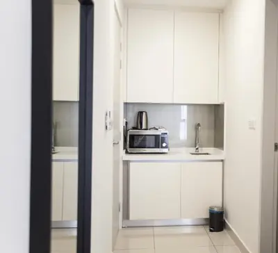 a kitchen with white cabinets and a microwave on a counter at KL Premium Dual Key Studio with KLCC view on the 56th floor in Kuala Lumpur