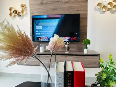 a vase with a flower and books in front of a tv at MVD41#Family Suite 8pax 3 Rooms M Vertica Velocity Mall Cheras IKEA Mytown Short Walk to MRT & LRT Maluri in Kuala Lumpur