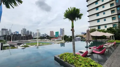 a pool with chairs and a palm tree and a building at Opus Residences Kuala Lumpur by Infini Suites in Kuala Lumpur