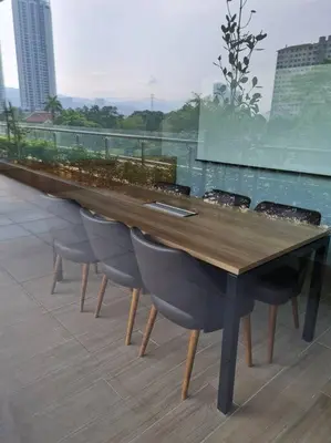 a long wooden table and chairs on a balcony at Neu Suites Near Gleneagles 10 minutes to KLCC in Kuala Lumpur
