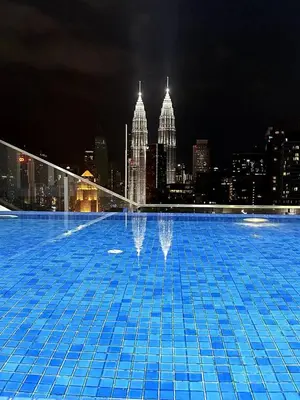 a large swimming pool with a city skyline at night at Maxhome Cozy at The Luxe in Kuala Lumpur