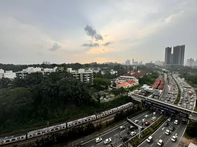 a city with a train and a highway with traffic at Immersed in the warmth and natural ambience in Kuala Lumpur