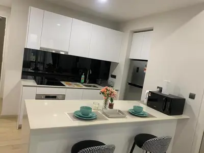 a kitchen with white cabinets and a table with chairs at Holiday Suites Star Residences in Kuala Lumpur