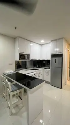 a kitchen with white cabinets and a black counter top at KL City Centre in Kuala Lumpur