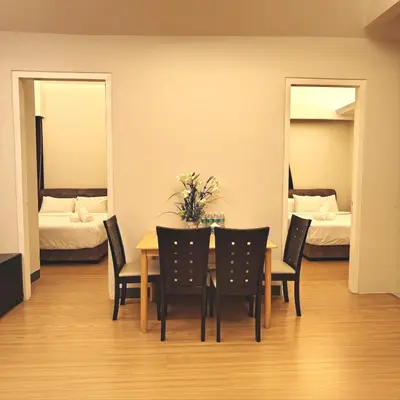 a dining room with a table and chairs and two beds at Swiss Garden Residence by Offex Suites KL in Kuala Lumpur