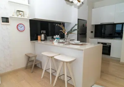 a white kitchen with a counter and stools in it at STAR RESIDENCE KLCC By GANTYA in Kuala Lumpur