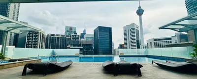 a rooftop pool with chairs and a city skyline at SOHO SUITES KLCC by DREAMS in Kuala Lumpur