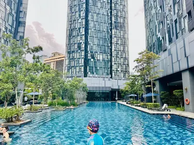 a man standing in front of a swimming pool with tall buildings at Star Residence KLCC By Starlight in Kuala Lumpur