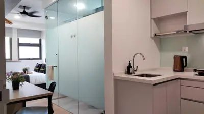 a kitchen with white cabinets and a sink and a table at Riveria Suites, KL Sentral by Homebrickz in Kuala Lumpur