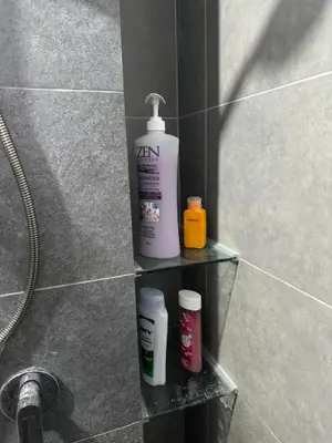 a shelf in a shower with a bottle of shampoo and other products at KL City Nue Suites Entire Condo 2R2B 3 plus 1 guests in Kuala Lumpur