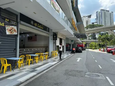 a person standing outside of a restaurant with yellow tables and chairs at KL City Nue Suites Entire Condo 2R2B 3 plus 1 guests in Kuala Lumpur