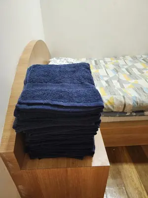 a pile of towels sitting on a wooden table next to a bed at 4R2B crest residences walk to klcc jln alor train 2station to bukitbintang water machine in Kuala Lumpur