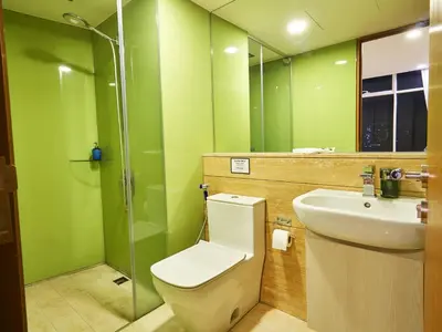 a green bathroom with a toilet and a sink at Vortex Apartments Kuala Lumpur in Kuala Lumpur