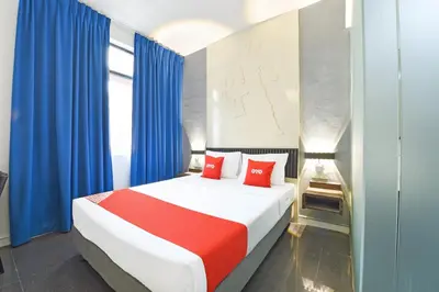 a bedroom with a bed with blue curtains and red pillows at Hotel O Pollodium Chinatown in Kuala Lumpur