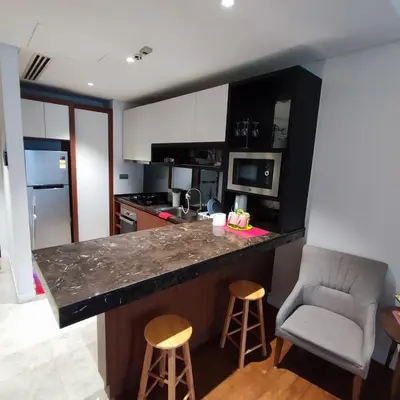 a kitchen with a counter and a bar with two stools at Anggun residence studio klcc in Kuala Lumpur