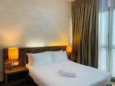 a bedroom with a bed with two lamps and a window at Regalia KLCC View by Ucare Suites in Kuala Lumpur