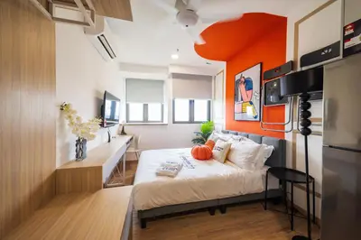 a bedroom with a bed with an orange wall at Riveria City KL Sentral by Sleepy Bear in Kuala Lumpur