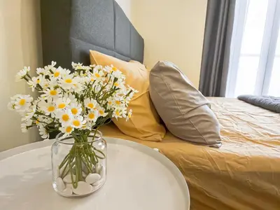 a vase of flowers on a table next to a bed at Setapak Central KL - Zetapark Spring Suites in Kuala Lumpur