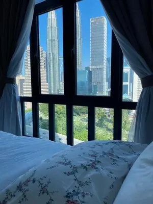 a bedroom with a view of a city from a window at KLCC Skyhomes near LRT in Kuala Lumpur