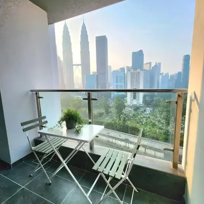 a table and chairs on a balcony with a view of the city at KLCC Skyhomes near LRT in Kuala Lumpur
