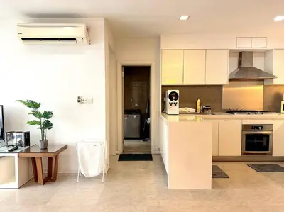 a kitchen with white cabinets and a table and a counter at Bintang Fairlane Residence, KLCC & City View - 2B1R in Kuala Lumpur
