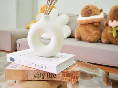 a vase sitting on top of a book on a table at Capybara Trion KL View in Kuala Lumpur