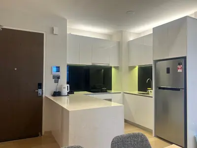 a kitchen with white cabinets and a refrigerator at Holiday Suites at Star in Kuala Lumpur