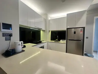 a kitchen with white cabinets and a stainless steel refrigerator at Holiday Suites at Star in Kuala Lumpur