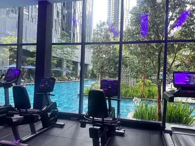 a gym with a pool seen through a window at Holiday Suites at Star in Kuala Lumpur
