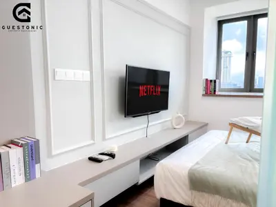 a bedroom with a tv on a white wall at Riveria City KL Sentral by Guestonic in Kuala Lumpur