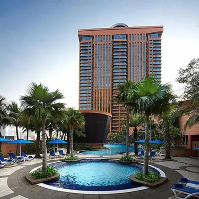 a hotel with a pool with palm trees and a tall building at Times Square Suite KL in Kuala Lumpur