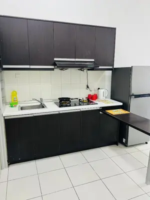 a kitchen with black cabinets and a sink and a stove at VUE Residences Hkl Klcc view in Kuala Lumpur