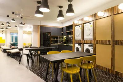 a dining room with tables and yellow chairs at Upstairs Downstairs CoLiving Kampung Pandan in Kuala Lumpur