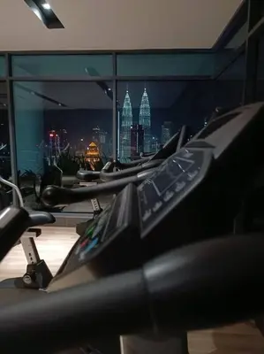 a row of exercise bikes in a gym with a city skyline at COL 14A Modern Infinity Pool KLCC View with Balcony in Kuala Lumpur