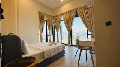 a bedroom with a bed and a desk and windows at Star Serviced Suite KLCC in Kuala Lumpur