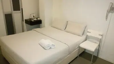 a white bed with two towels on top of it at T-Hotel Bukit Bintang in Kuala Lumpur