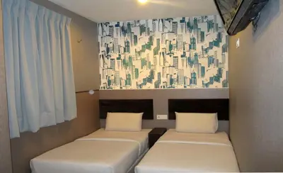three beds in a room with a painting on the wall at T-Hotel Bukit Bintang in Kuala Lumpur