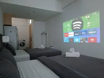 a room with two beds and a large screen on the wall at COL 93A 2Queen bed Balcony KLCC View Family Suites in Kuala Lumpur