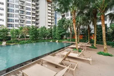 a swimming pool with lounge chairs and palm trees at Japandi 1BR Agile Bukit Bintang by RumaBnB in Kuala Lumpur