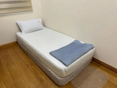 a small bed in a corner of a room at Hushed Dorm KL in Kuala Lumpur