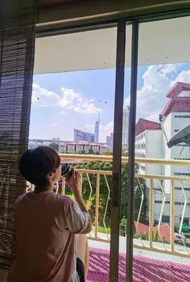 a woman taking a picture of the city from a window at Tatami MUJI Relax 5p City center Staycation MRT in Kuala Lumpur