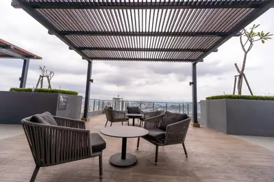 a patio with chairs and tables on a roof at Neu Suites By Cozy Unit L20RB near KLCC & Jelatek LRT in Kuala Lumpur