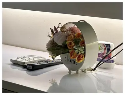 a vase of flowers on a desk with a remote control at Setapak Central Premium Suites in Kuala Lumpur