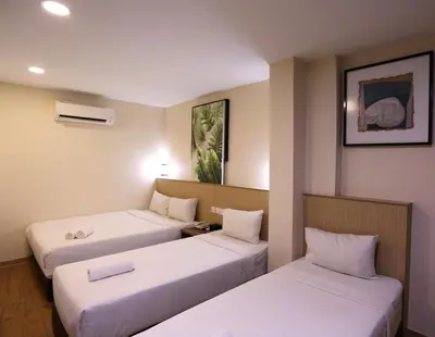 two beds in a room with white sheets at ECO Hotel at BBCC in Kuala Lumpur