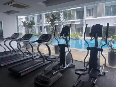 a gym with cardio machines in front of a swimming pool at Cozy Downtown 2BR at M Suites, Embassy Row in Kuala Lumpur