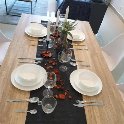 a wooden table with white plates and wine glasses at Arte Plus Jalan Ampang, KLCC Level 35 in Kuala Lumpur