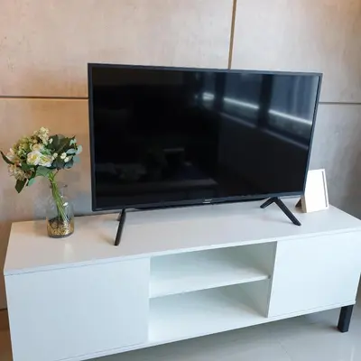 a television on a white stand with a vase of flowers at Arte Plus Jalan Ampang, KLCC Level 35 in Kuala Lumpur
