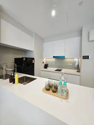 a kitchen with white cabinets and bottles on a counter at Alfa Bangsar by City Keys in Kuala Lumpur