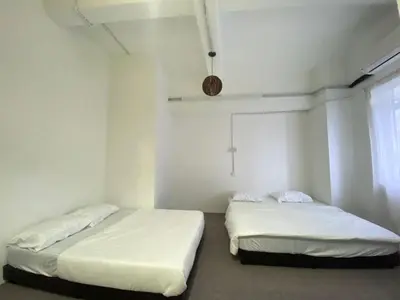 two beds in a room with white walls and a window at Bright Star Inn in Kuala Lumpur